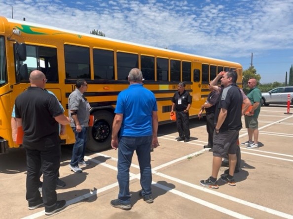 A group of men observe an electric school bus.